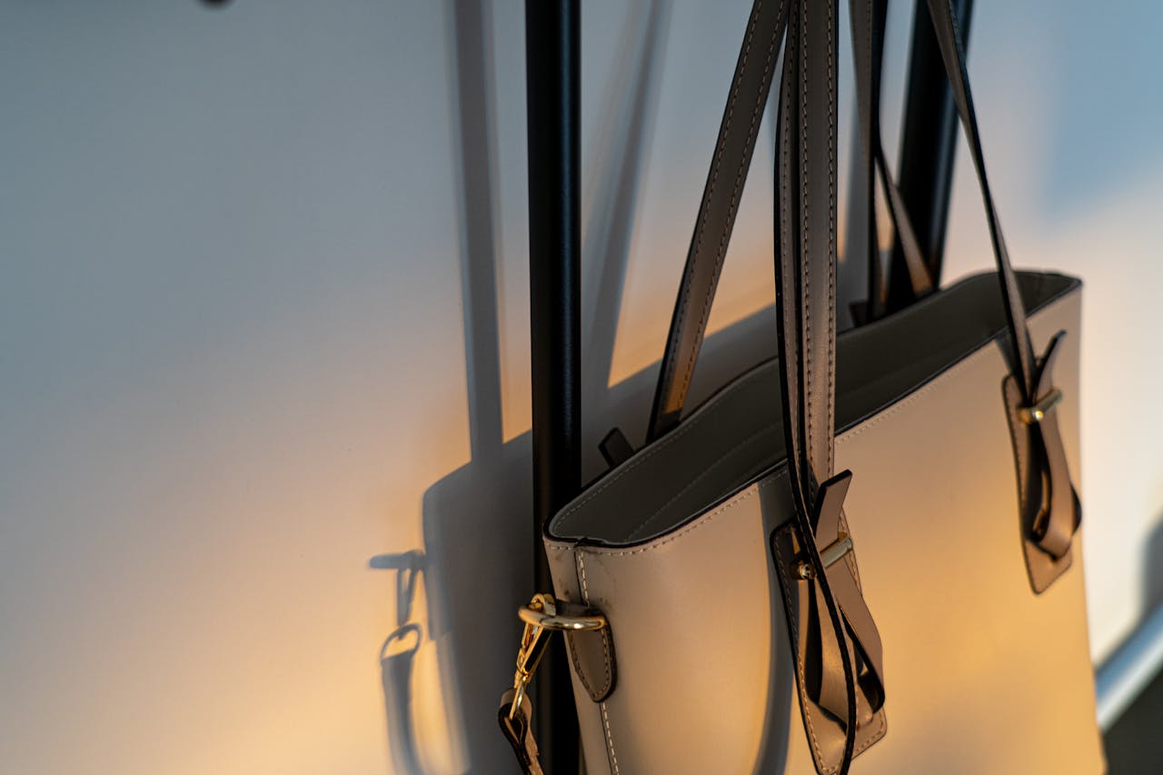 services-01 High-quality leather handbag elegantly hanging on a wall with soft lighting.